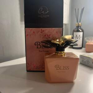 Säljer en elegant Bliss Pour Femme parfym från Classic Collection. Flaskan är i en mjuk persikofärg med en lyxig guldfärgad blomma som lock. Förpackningen är rosa med blommönster och rymmer 100 ml Eau De Parfum. Perfekt för den som vill ha en sofistikerad doftupplevelse. 🌸 Oanvänd