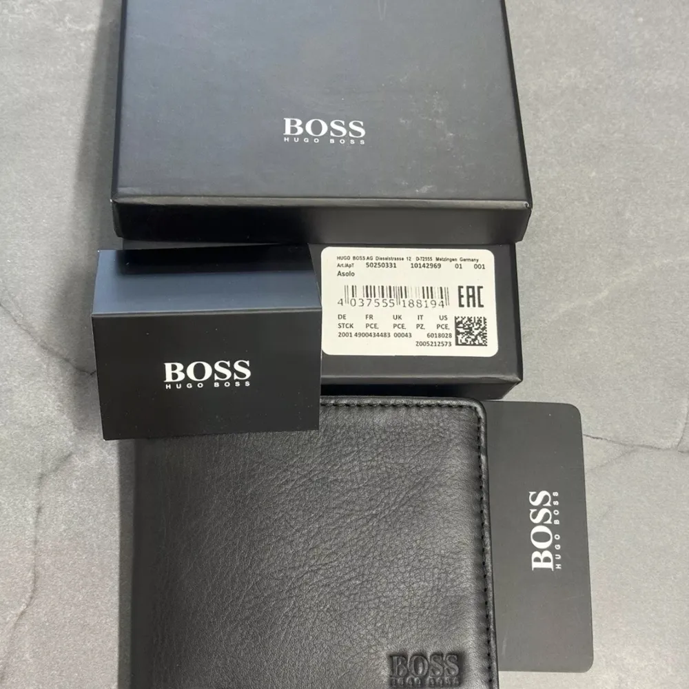 Leather Bifold Wallet With Embossed logo and Coin Pocket style  A refined billfold wallet by BOSS including a coin pocket. Featuring subtle embossed logos both inside and out, this sleek accessory is crafted in micro-grained leather with a soft feel and matte finish.  Will come with original  box . Väskor.