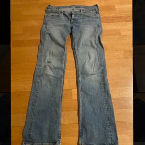 Blå low waist jeans - Säljer ett par klassiska blå raka/bootcut jeans i bra skick. De har en snygg tvättad look och är perfekta för vardagsbruk. Jeansen har fem fickor och en dragkedja med knapp framtill. Passar perfekt för en avslappnad stil.