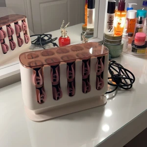Hårvärmespolar från Remington  - Säljer ett set med hårvärmespolar i en snygg rosa och vit design. Perfekt för att skapa vackra lockar hemma. Setet kommer med en praktisk förvaringsstation som värmer upp spolarna snabbt. Perfekt för både kort och långt hår!