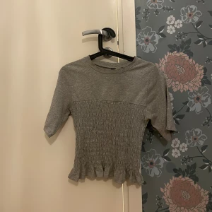 Hm smockad t shirt  - Säljer en söt grå topp från Hm i storlek XS. Den är slutsåld på hm sidan 💕💕