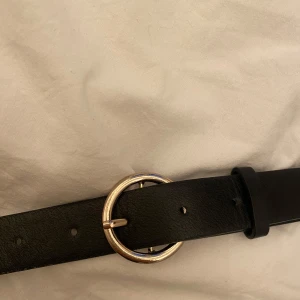 Svart skärp H&M - Säljer ett stilrent svart skärp i skinn med ett spänne i guld från H&M! Varan är i fint skick utan skador eller slitningar💕Passar storlek XS-M