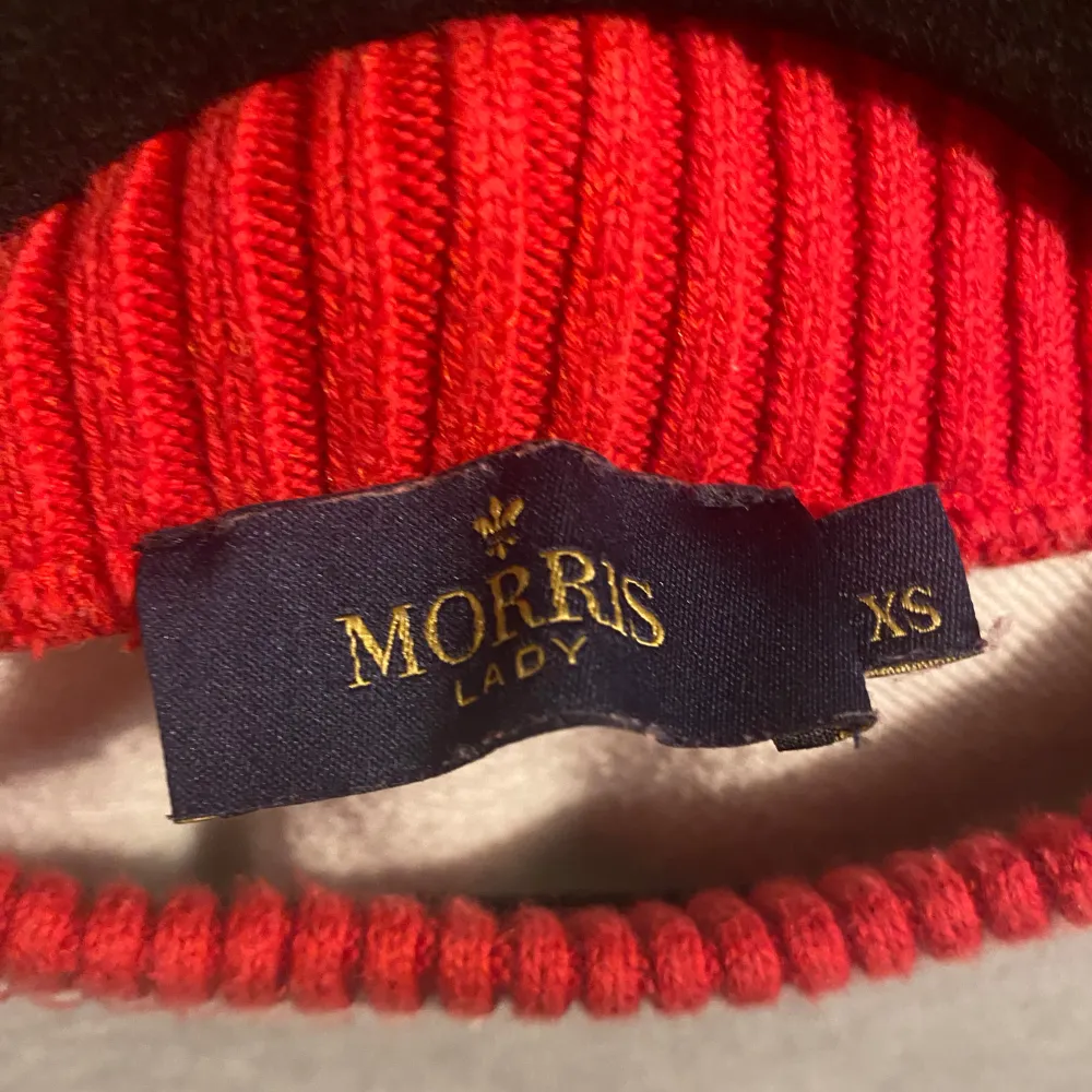 Säljer en snygg grå sweatshirt från Morris med texten 'MORRIS' i vit frotté på bröstet. Den har en cool ribbad krage i rött och vitt som ger en sportig look. Perfekt för både vardag och chill! 🩶. Hoodies.