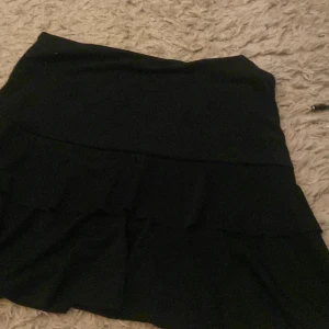 Svart kjol med volanger från missäy - Säljer en superfin svart kjol med volanger. Den är ganska mid waist men man kan vika ner den till Low waist. Ifrån missäy, den är strl L/XL men den är väldigt stretchig, jag har strl XS i nästan allt och den passar mig perfekt så jag skulle säga att denna kjolen passar de flesta storlekar. 