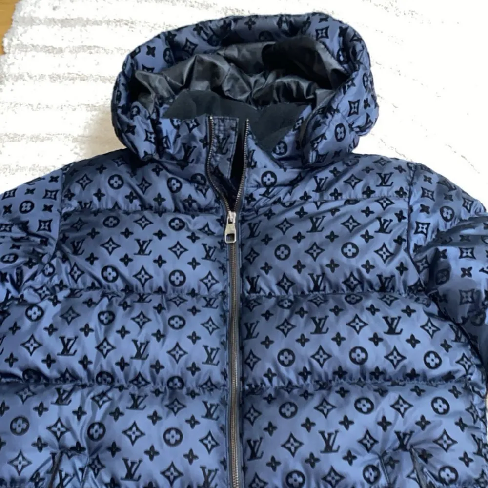 Säljer en snygg mörkblå pufferjacka från Louis Vuitton med deras ikoniska monogrammönster. Jackan har en dragkedja och en mysig huva, perfekt för kyliga dagar. Den är i mycket bra skick och passar perfekt för både höst och vinter.  Diskuteras vid snabbt affär.  Använd 3-4 gånger!. Jackor.