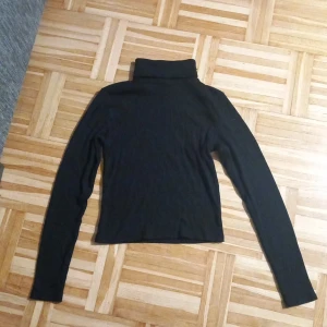 Svart polotröja från FB Sister - Säljer en stilren svart polotröja från FB Sister i storlek M. Tröjan är ribbad och har långa ärmar, perfekt för kyliga dagar. Den är i mycket bra skick och passar både till vardags och lite finare tillfällen. Ett måste i garderoben! 🖤 Vill bara tillägga att den är liten I storleken. 