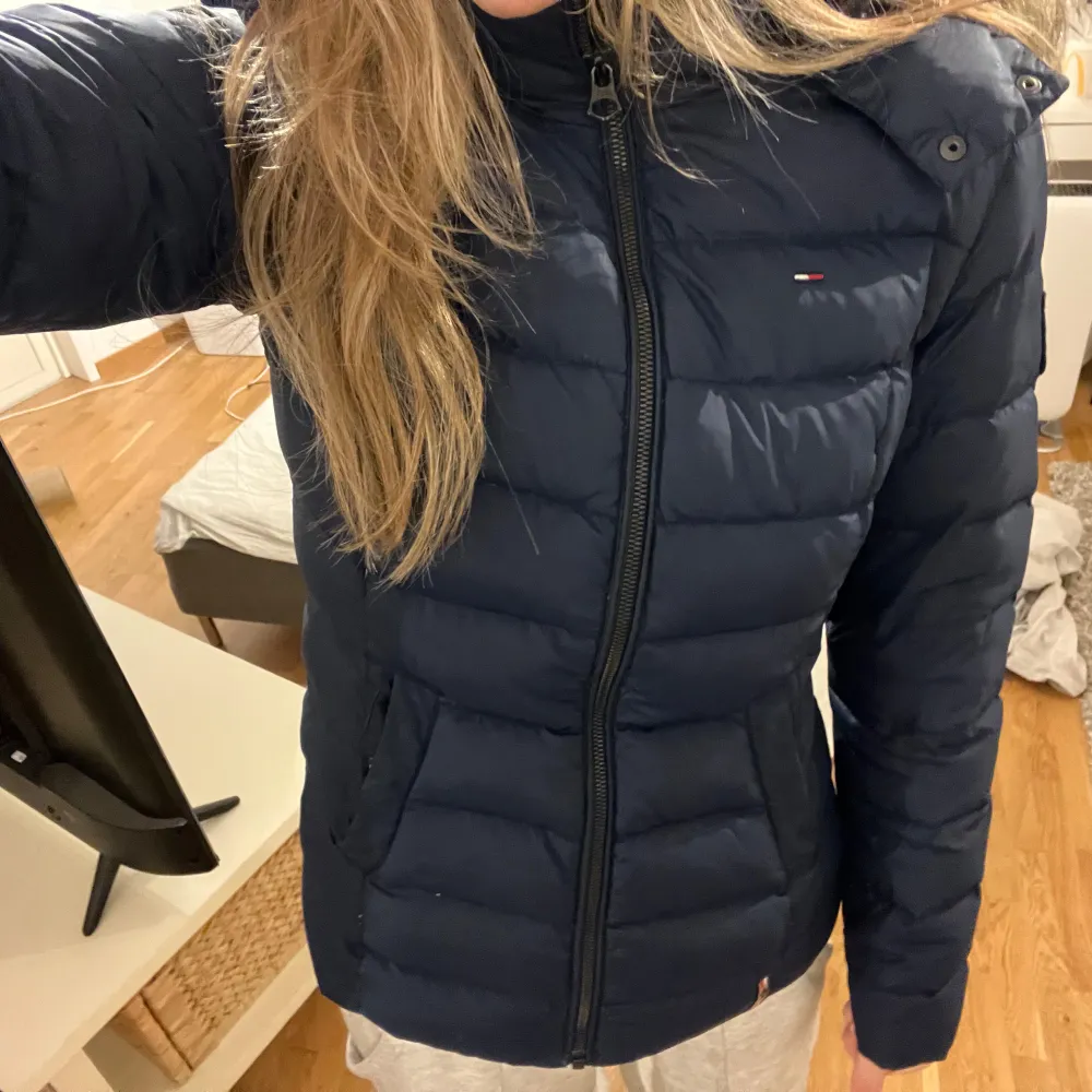 Säljer en snygg mörkblå dunjacka från Tommy Hilfiger. Jackan har en mysig pälskantad huva och dragkedja framtill. Perfekt för kalla vinterdagar! Den är i mycket bra skick och passar både till vardags och lite finare tillfällen❤️är i storlek M men passar mer som en S.. Jackor.