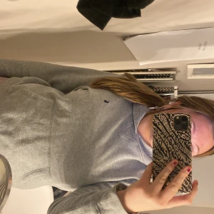 Grå hoodie från Polo Ralph Lauren - Säljer en snygg och bekväm grå hoodie från Polo Ralph Lauren. Den har en klassisk design med en liten logga på bröstet och en stor ficka framtill. Perfekt för kyliga dagar eller mysiga hemmakvällar. Passar till det mesta i garderoben!