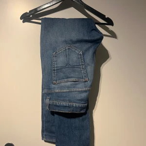 Blå jeans  - Säljer ett par snygga blå jeans från tiger or sweden. Perfekta för vardagsbruk och passar till det mesta. De har en klassisk look med en smalare passform. Perfekta för både höst och vår! Storlek 30/32 i modellen evolve 