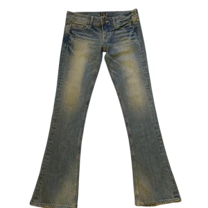 Blå bootcut jeans från SLY - Snygga blå bootcut jeans från SLY i bra skick. De har en klassisk femficksdesign och en knappgylf. Perfekta för en avslappnad stil med en touch av retro. Passar både till vardags och festligare tillfällen.