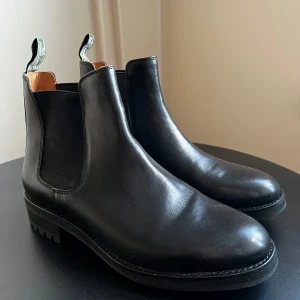 Svarta Chelsea boots från Ralph Lauren - Snygga svarta Chelsea boots i skinn från Polo Ralph Lauren. De har en klassisk design med elastiska paneler på sidorna och en robust sula för extra grepp. Perfekta för både vardag och fest! 🖤