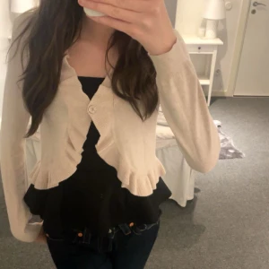 Beige kofta med volangdetaljer - Säljer en superfin beige kofta med volangdetaljer. Den har långa ärmar och knäpps framtill med en knapp köpte för 2 månad sen men används inte den är superfin och är i väldigt fint skick💕😊priset kan diskuteras om man vill sänka