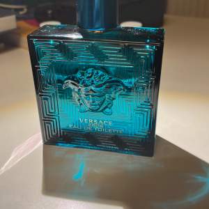 Säljer en flaska Versace Eros Eau de Toilette. Flaskan är i en snygg turkosblå färg med ett elegant mönster och Versaces ikoniska Medusa-logga. Den har en lyxig och maskulin doft som passar perfekt för både dag och kväll. Flaskan är 100 ml med 50ml kvar och kommer i originalförpackning.