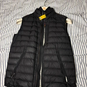 Svart dunväst Parajumpers - Säljer en svart dunväst från Parajumpers i storlek XS. Västen är superlätt och perfekt för höst och vår. Västen har en fläck på insidan (Se sista bilden) Men syns ju då inte när man använder den. Den är köpt på NK och kvitto finns. Priset är inte hugget i sten