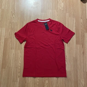 Röd t-shirt med logga - Säljer en snygg röd t-shirt från abercrombie i helt nytt skick då den aldrig har använts. Skön, mjuk bra t-shirt! Endast 75 kr för denna! Skriv gärna om du har någon fråga eller fundering! Mvh Sthlm garderoben!