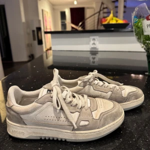 Beige sneakers från Axel Arigato - Säljer ett par snygga beige sneakers från Axel Arigato i bra skick. De är slitna i hälen men annars bra. Nypris 2250