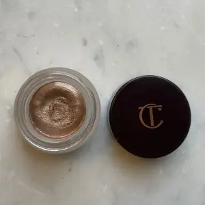 En krämig ögonskugga i färgen Oyster Pearl från Charlotte Tilbury. Den har en skimrande, pärlemorskimrande nyans. Perfekt för både vardag och fest! Kommer i en snygg glasburk. Endast testad på hand vid ett tillfälle.