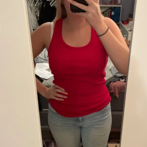 Rött linne - Säljer ett snygg rött linne i ett mjukt och stretchigt material. Perfekt för sommardagar eller som ett lager under en jacka. Toppen har en enkel design med rund halsringning och en tight passform. Linnet är i bra skick då den endast används ett fåtal gånger, köparen står för frakten💖