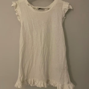 Vit tröja från Scotch & Soda - Säljer en söt vit tröja från Scotch & Soda med volangdetaljer vid ärmar och nederkant. Perfekt för sommardagar eller en avslappnad fest. Klänningen är i bra skick och har en luftig passform. Superfin och enkel att matcha med olika accessoarer!