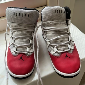 Nike Air Jordans i rött och vitt - Säljer ett par snygga Nike Air Jordans i rött och vitt. Skorna har en klassisk design med snörning och den ikoniska Jumpman-loggan. Perfekta för både vardag och sportiga aktiviteter. De är i mycket bra skick och redo för nya äventyr!