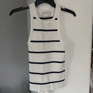 Vit och marinblå randig linnetopp från Neo Noir - Snygg och stilren vit linnetopp från Neo Noir med marinblå ränder. Perfekt för sommardagar eller en avslappnad dag på stan. Toppen är ärmlös och har en klassisk passform som är både bekväm och trendig.