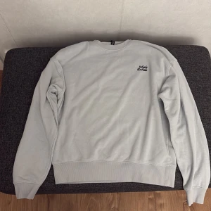 Grå sweatshirt med tryck - Säljer en stilren grå sweatshirt i mycket bra skick. Den har ett litet tryck fram och ett större grafiskt tryck på ryggen med texten 'Inhale Exhale'. Perfekt för både vardag och avslappnade tillfällen. Mjuk och bekväm med ribbade muddar.