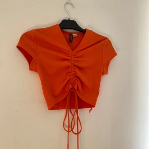 Orange topp - Topp från H&M använd en gång så i nyskick! Snöret är rätt långt går att knyta som man vill o spänna åt som man vill.