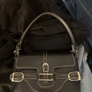 Axelremsväska  - Axelremsväska med metallspänne och detaljer