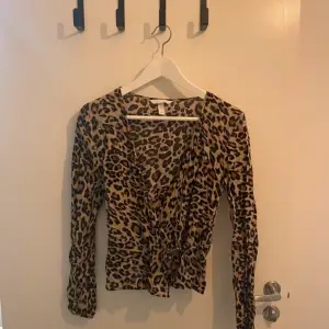 Säljer en superfin leopardmönstrad omlottkofta med knytband i midjan. Den har långa ärmar och är perfekt för att ge en vild touch till din outfit. Koftan är i ett mjukt och bekvämt material, perfekt för både vardag och fest!