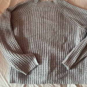 Grå stickad tröja från 157 - Säljer en supermysig ljus blå stickad tröja från 157. Den har en snygg, texturerad design och är perfekt för kyliga dagar. Tröjan har långa ärmar och en bekväm passform. Perfekt för både höst och vinter!