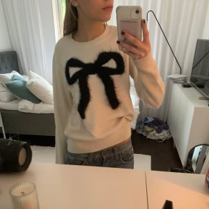 Stickad tröja med rosett - Vit stickad tröja med svart rosett, bra skick, från Holly&Whyte, storlek S 💗 köpare står för frakt