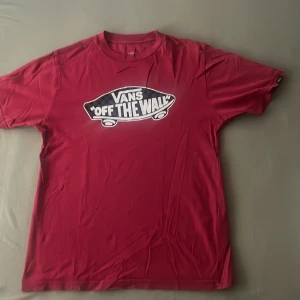 Röd Vans T-Shirt  - Detta är en vin röd vans t-shirt i storleken M för barn mellan åldrarna 10-12. Den har ett litet hål nedan för halsen.