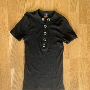 T-shirt - T-shirt med knappar på framsidan. Storlek XL, men skulle säga att den passar mer S/M. Mycket bra skick, inga defekter. 