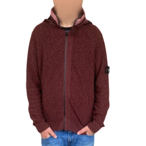 Vinröd hoodie med dragkedja - Säljer en snygg vinröd hoodie från Stone Island. Den har en dragkedja framtill och en cool logga på ärmen. Perfekt för höst och vinter, den funkar till vardag och är extremt frän och unik!