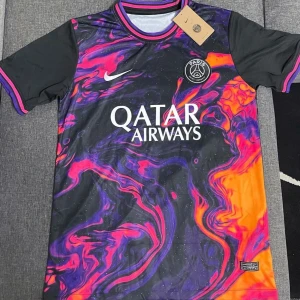 PSG fotbollströja med färgglatt mönster - Säljer en supercool PSG fotbollströja från Nike. Den har ett unikt och färgglatt mönster i svart, lila, rosa och orange. Tröjan är kortärmad och har klubbens emblem på bröstet samt Qatar Airways som sponsor. Perfekt för dig som vill sticka ut på planen!