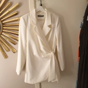 Kavaj - Kavaj från Gina tricot, med "omlott" knäppning och knytband i sidan. I nyskick, aldrig använts. 