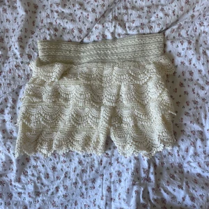 Vita spetsshorts - Säljer ett par superfina vit spetshorts som är perfekt för sommaren! Shortsen har ett vackert mönster och en elastisk midja för en bekväm passform. Den är kort och passar perfekt till både vardag och fest. 🕊️