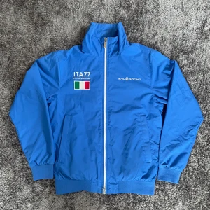 Ovanlig Gammal Ljusblå ”Sail Racing” Höstjacka  - Extremt ovanlig ljusblå Sail Racing Höstjacka, från internationella Italienska laget inom segling. Dessa produceras inte längre och säljs för mer än 4000kr. Storlek S. Knappt använd, inga märken/hål/smuts och kvaliten är väldigt bra 😚.