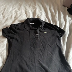 Svart t shirt  - En svart Lacoste T-shirt i st 42 men skulle mer säga att de är en S-M