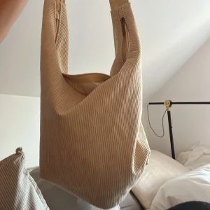 Väska - Ungefär likadan väska som den andra jag säljer. Men det som skiljer är materialet och då denna är randig och den andra glansig.