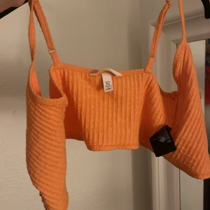 Orange ribbad topp - Säljer en superfin orange ribbad topp i storlek S. Den är ärmlös och har smala axelband, perfekt för sommaren! Toppen är croppad och har en härlig, ljus orange färg som verkligen poppar. Perfekt för en dag på stranden eller en somrig fest! 🌞