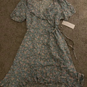 Klänning - Blå blommig klänning, aldrig använd,lappen sitter kvar, Stl 36 Köparen står för frakten 