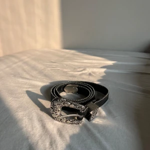 Svart läderskärp med silverdetaljer - Coolt skärp, vet ej om det är läder eller läderimitation. Knappt använt och bra skick!