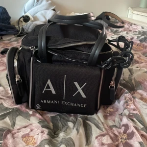 Armani väska - Armani väska som är fin, man kan packa in mycket i den och den har 6 fickor. Man kan ha den vid axeln eller bära upp den!