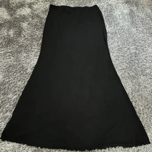 Svart ”glittrig” maxikjol  - ”Solid lettuce hem mermaid maxi skirt” Cider. Svart ”glittrig” maxikjol i stretchigt material. Aldrig använt, har lappen kvar från köpet. Jättefin men har aldrig fått användning av den.