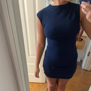 Mörkblå klänning  - Storlek 34, bra skick, assymatriska ärmar.