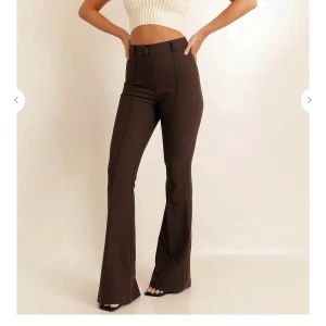 Bruna utsvängda byxor från Chiquelle - Snygga bruna byxor från Chiquelle med utsvängda ben och hög midja. Perfekta för en trendig look. Byxorna har en stilren design med dragkedja och knapp framtill. Ordinarie pris 599. 