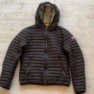 Svart pufferjacka från Colmar - Säljer en svart pufferjacka från Colmar med huva och dragkedja. Jackan är i gott sick bortsett från lite defekter på högra vikan. Model är 170 cm och väger 55. Hör av er vid funderingar. 