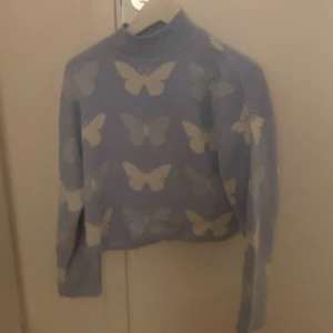 Ljusblå stickad tröja med fjärilsmönster - Säljer en söt ljusblå stickad tröja från H&M med fint fjärilsmönster på. Varm och perfekt nu till vintern/våren! 