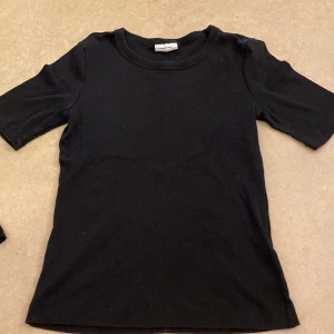 Svart ribbad t-shirt från Gina Tricot - Säljer en stilren svart ribbad t-shirt från Gina Tricot. Perfekt basplagg med korta ärmar och rund halsringning. Passar till alla tillfällen! I storlek m, men passar absolut för s och xs också!❤️🫶🏼🫶🏼